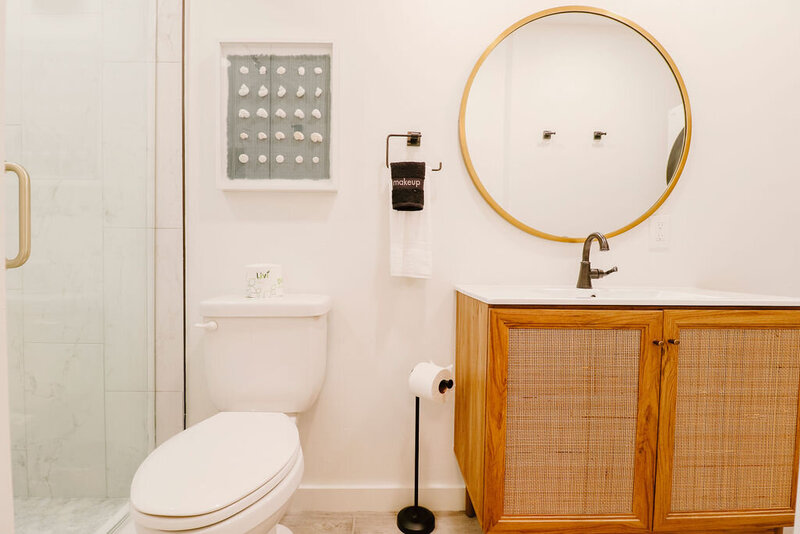 bathroom with wood cabinet and round mirror