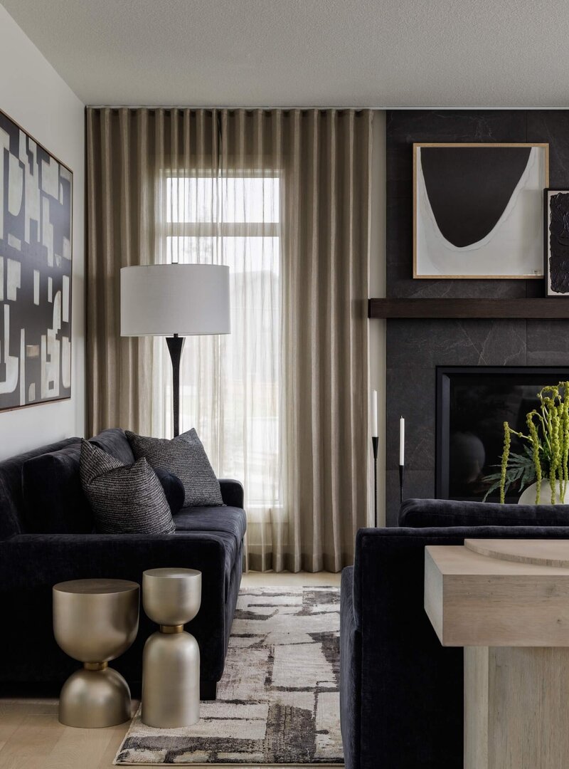 A cozy living room with charcoal upholstered sofas, gold accents and abstract black and white art. 