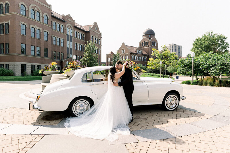 bride and groom in front of classic wedding car