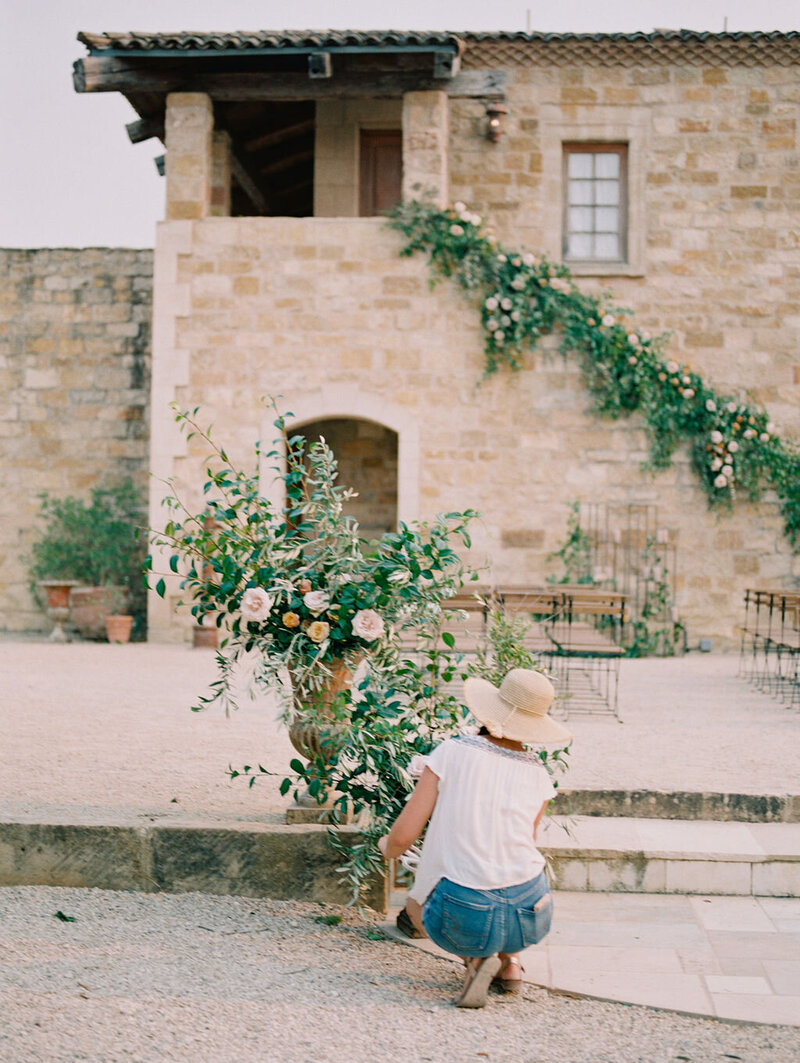 Florist with sun hat working on romantic floral urns at sunstone winery