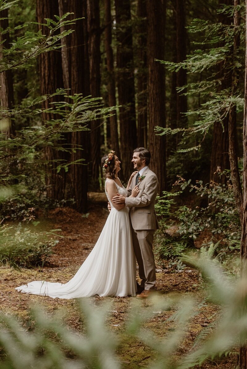 Couple laughing and embracing in the Mendocino redwoods on their wedding day
