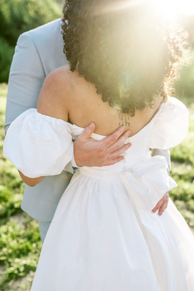 Light shining from behind a bride and groom embracing, representing the photography style of Eugene wedding photographer Among the Oaks. 