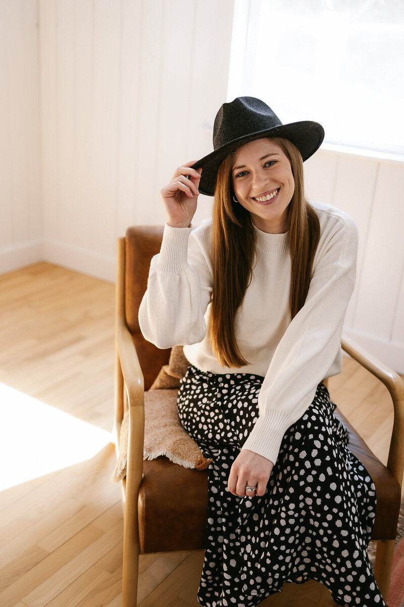 Laurel of Laurel Deane Creative smiling and sitting at a counter while holding a coffee cup