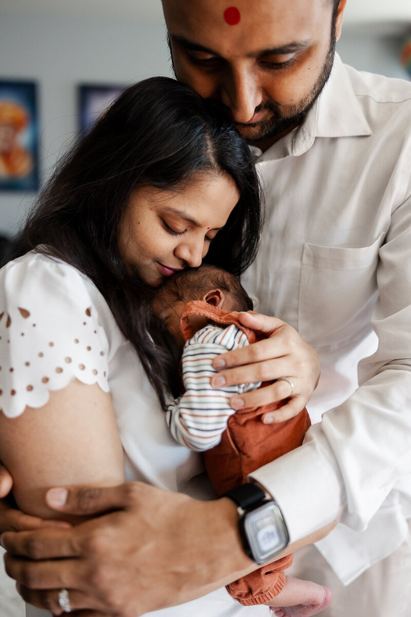In-home lifestyle newborn session of a family cuddling and looking at their newborn baby in St. Louis, Missouri. 
