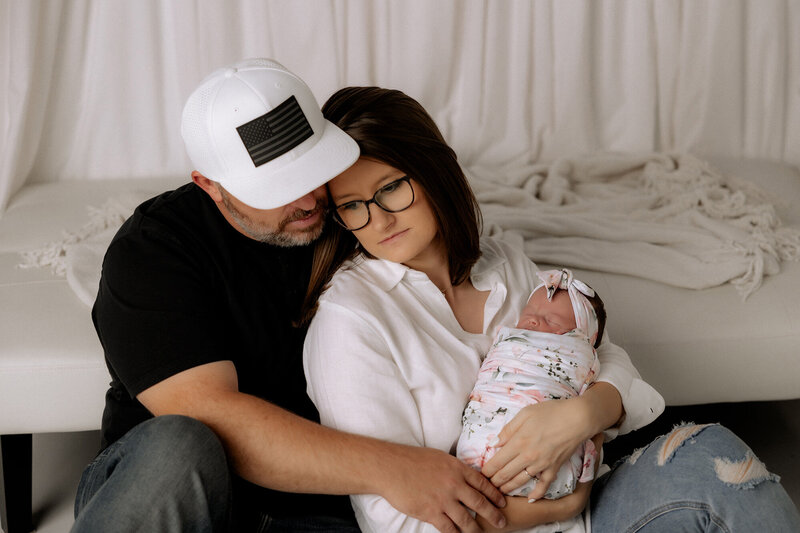 couple sitting on floor in studio holding baby