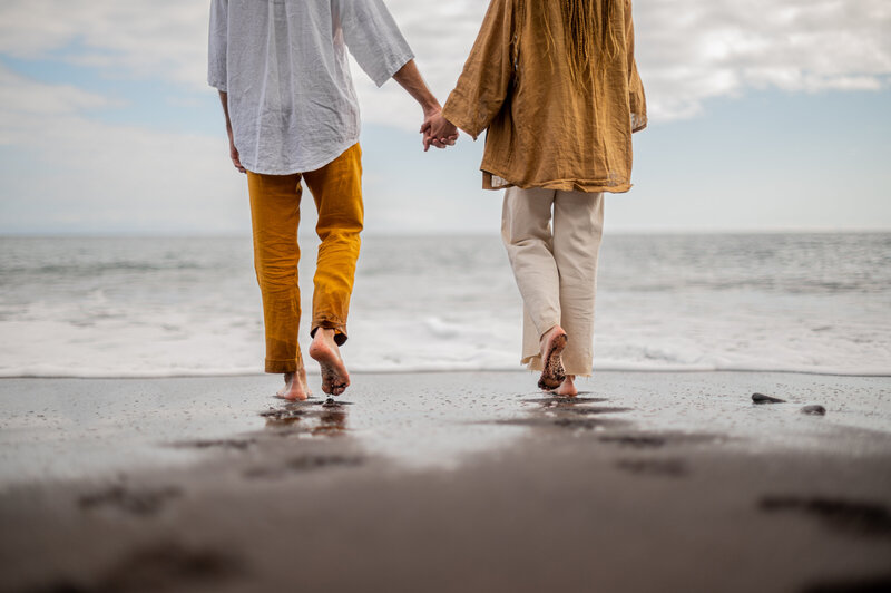 Zwei Menschen gehen Hand in Hand am Strand spazieren.