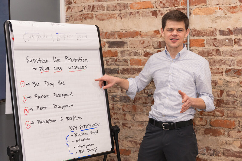 Man in business casual outfit pointing to a tripod paper board during a meeting in Atlanta GA
