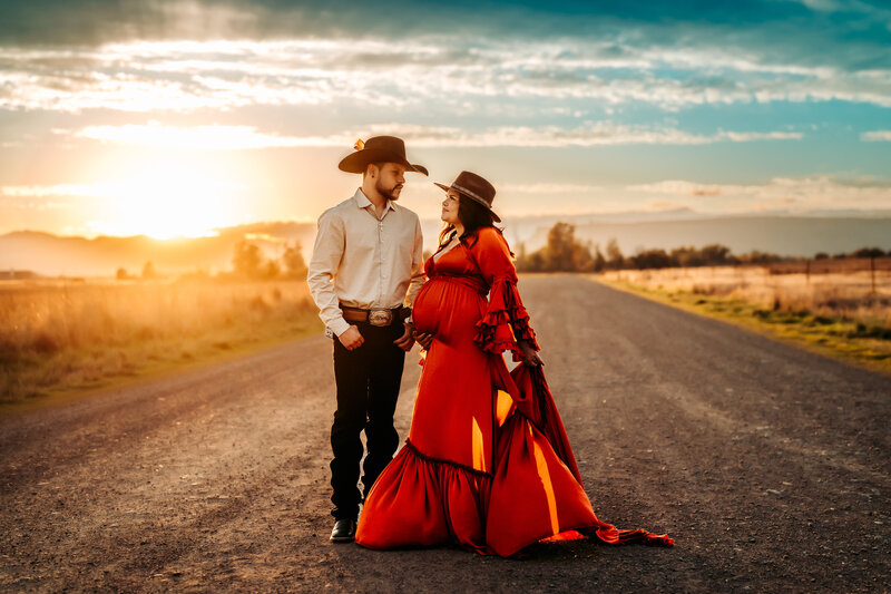 Family Photographer, a man and woman hold hands on a country road, they wear cowboy hats