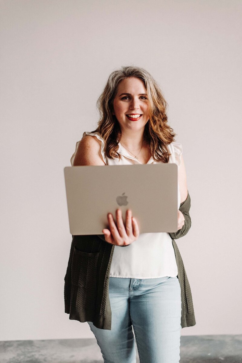 kristin pruis, web designer, smiling with an open laptop computer