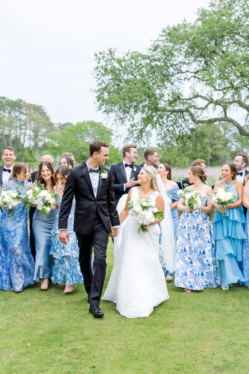 bride and groom holding hands while surrounded by their wedding party