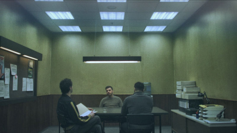 A handheld-style frame of a young man walking through a graffiti-covered alleyway.