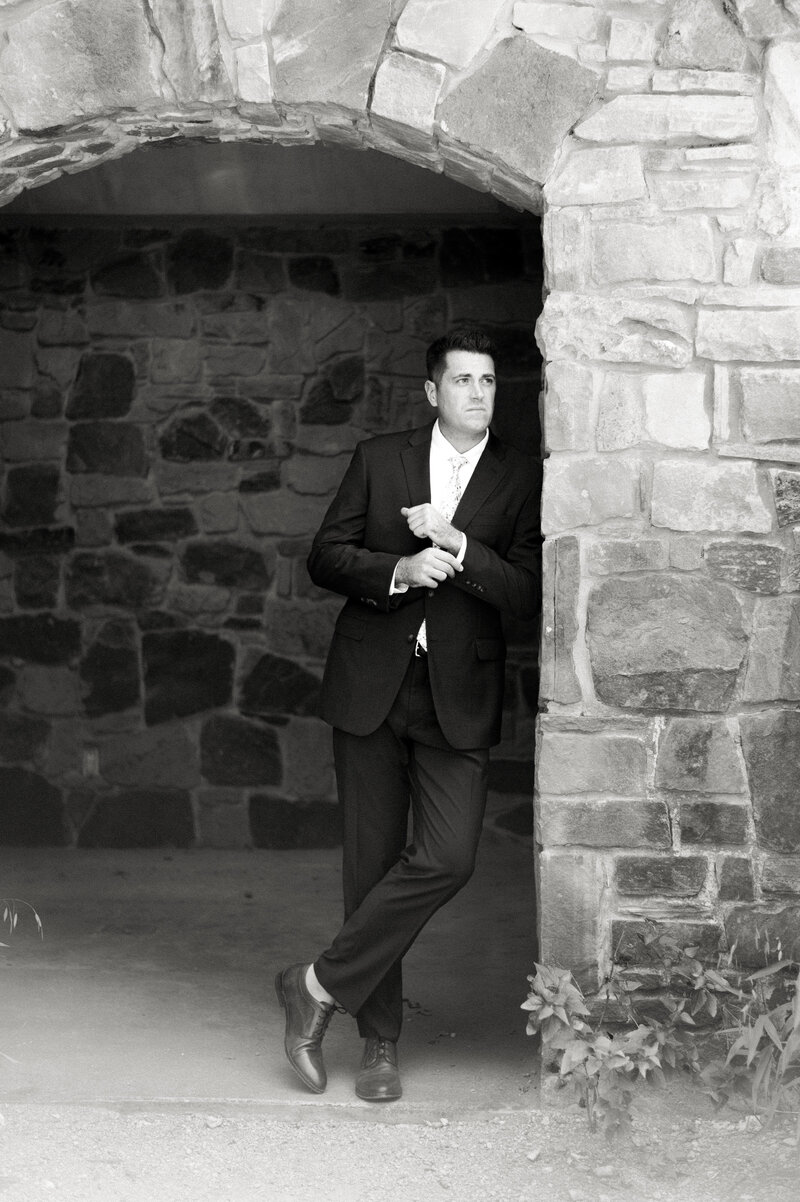 black and white portrait of groom under brick archway at ladybird johnson wildflower center by austin wedding photographer