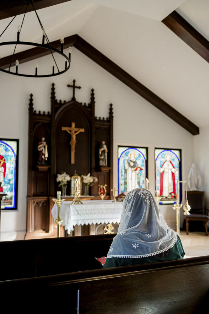 a young woman wearing a veil sitting in a Catholic church
