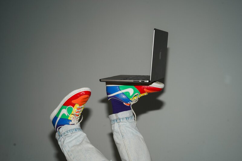 Laptop being held up by colorful sneakers