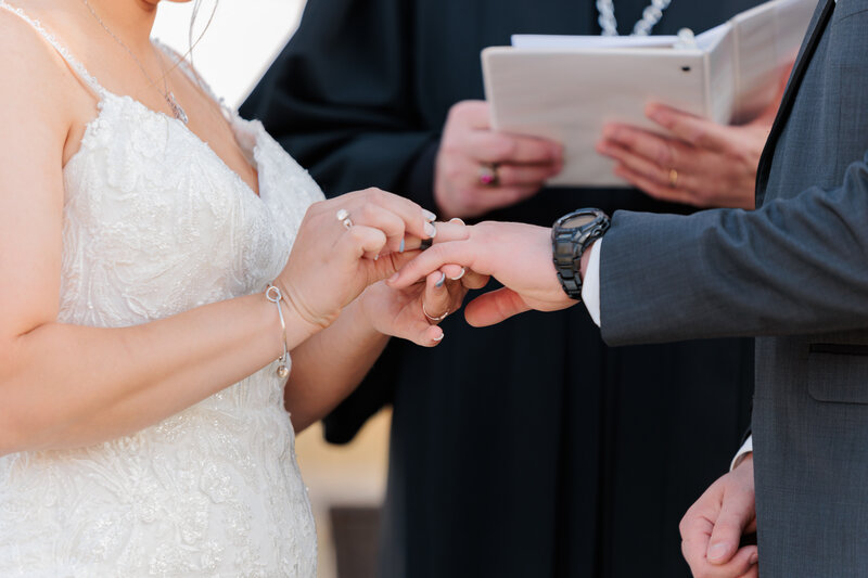 officiant in blue reads the wedding script to bride and groom along a lake shore captured by Scranton Wwedding Photographer Eric Boylan
