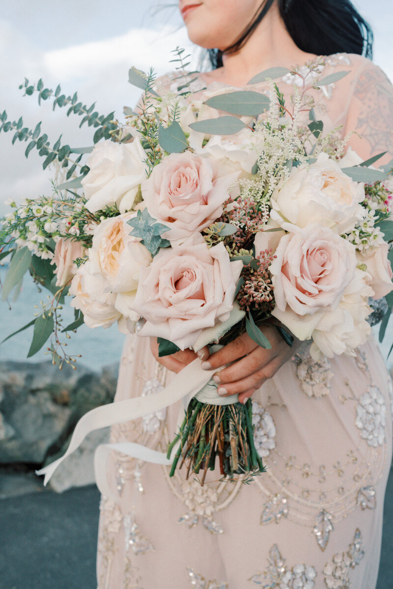 bride holding gorgeous bouquet of quicksand roses and greenery