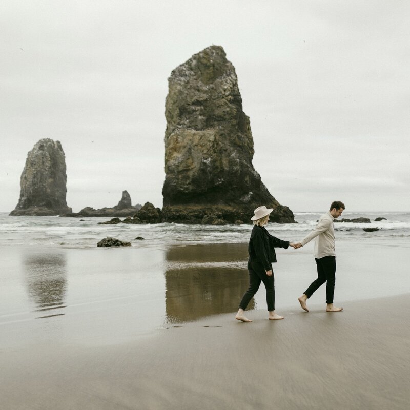 Couple walking along Cannon beach in Oregon