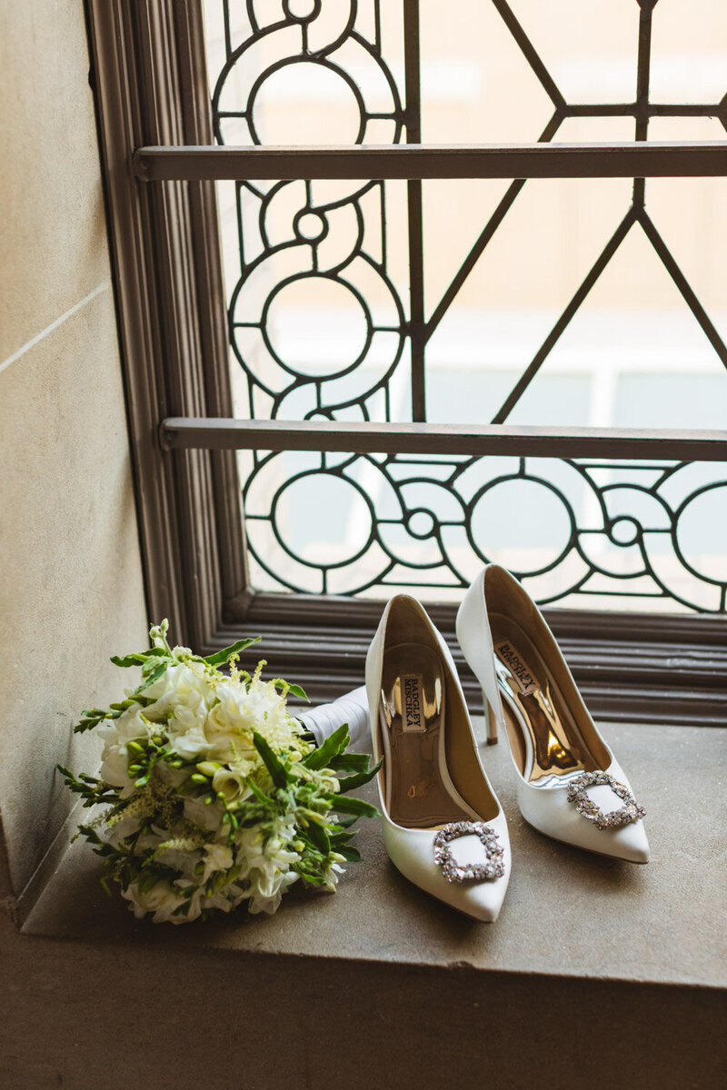 White bridal heels and bouquet placed by window