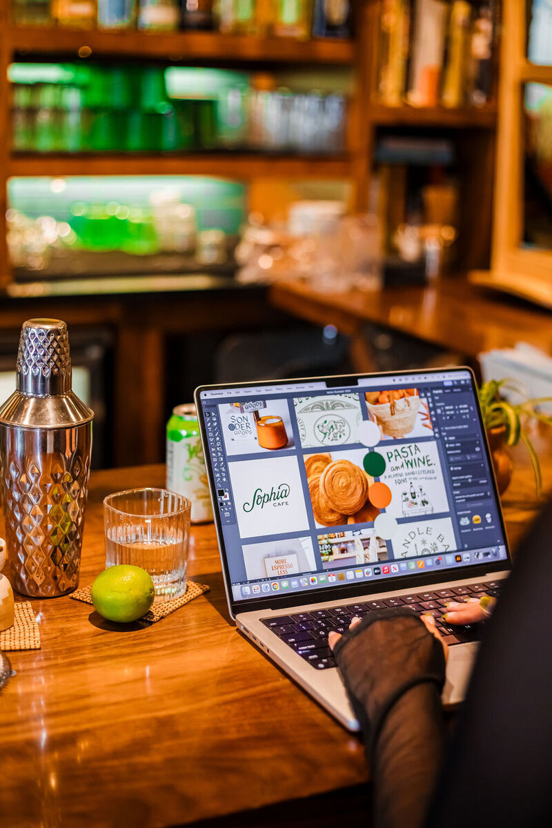 A designer works on a computer with 9 different images, showing examples of photography, typography, and logo ideas with a sample color palette of greens and oranges