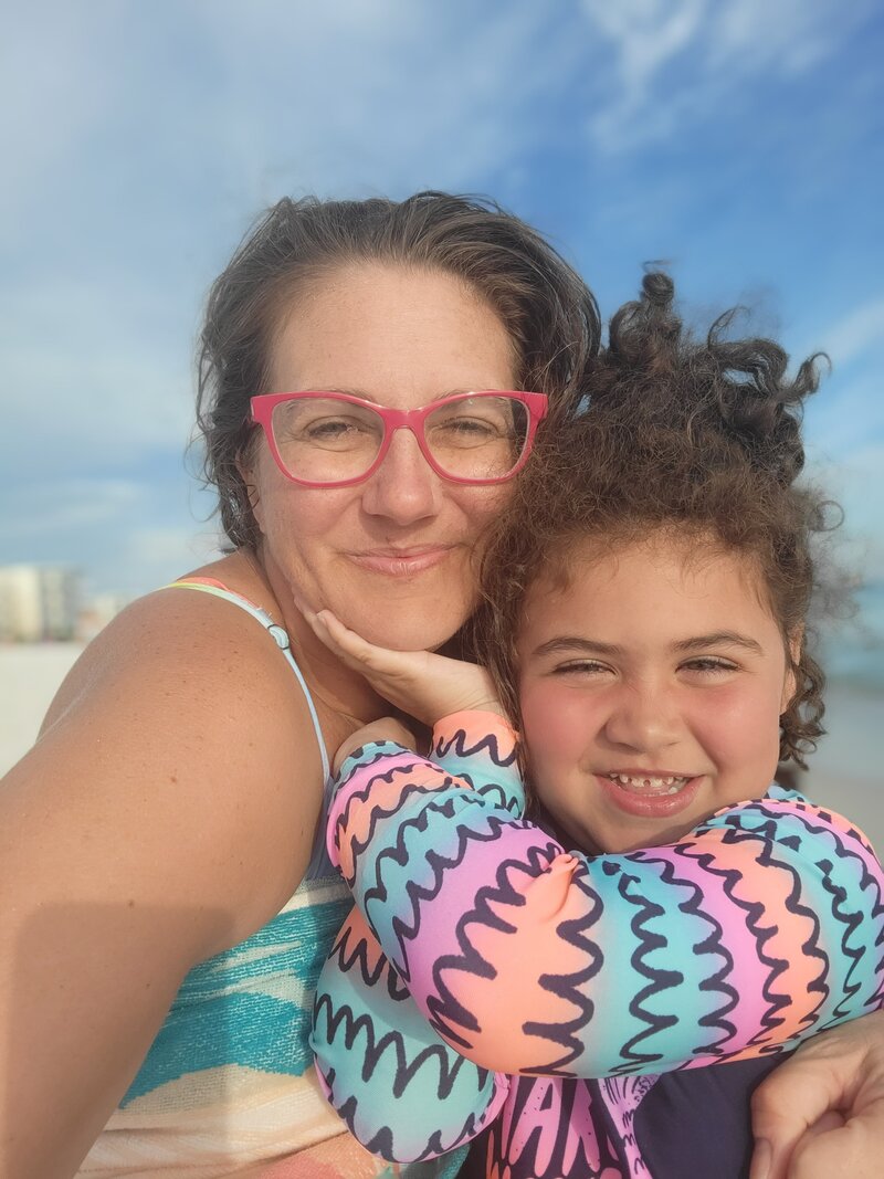 smiling mom and daughter on the beach