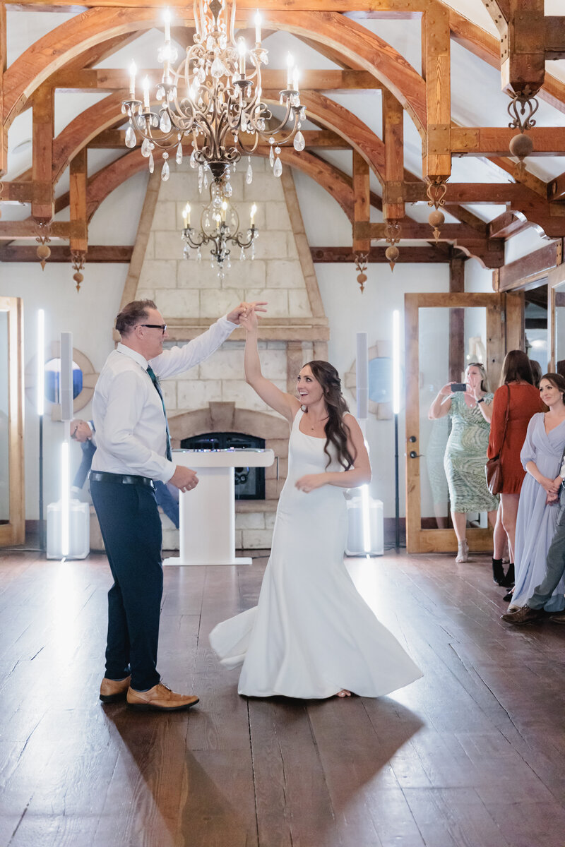 A father twirls his daughter in her wedding dress