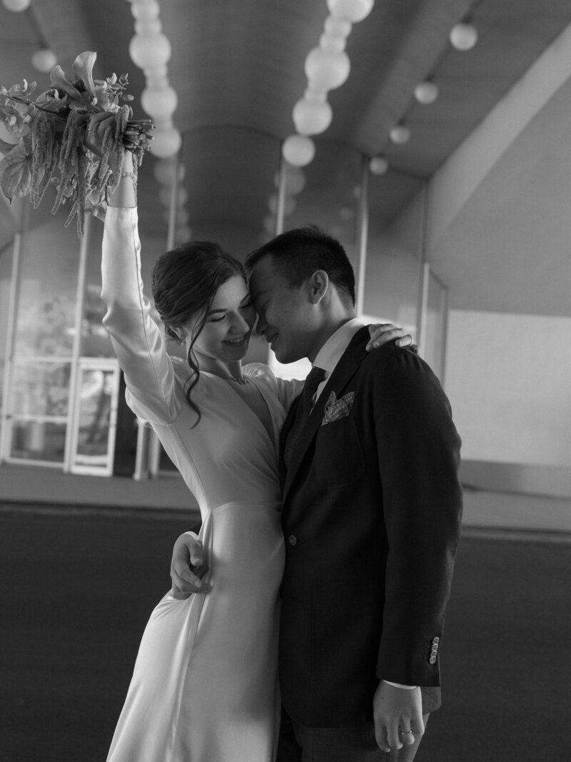Black and white portrait of couple smiling close outside Civic Center.