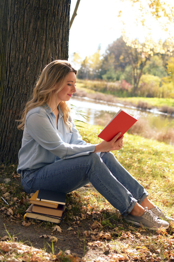 Middle-grade fantasy fiction  storyteller, Katie Mohar reading by tree.