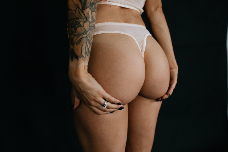 Woman in lingerie holding backside by Boudoir by Kiella