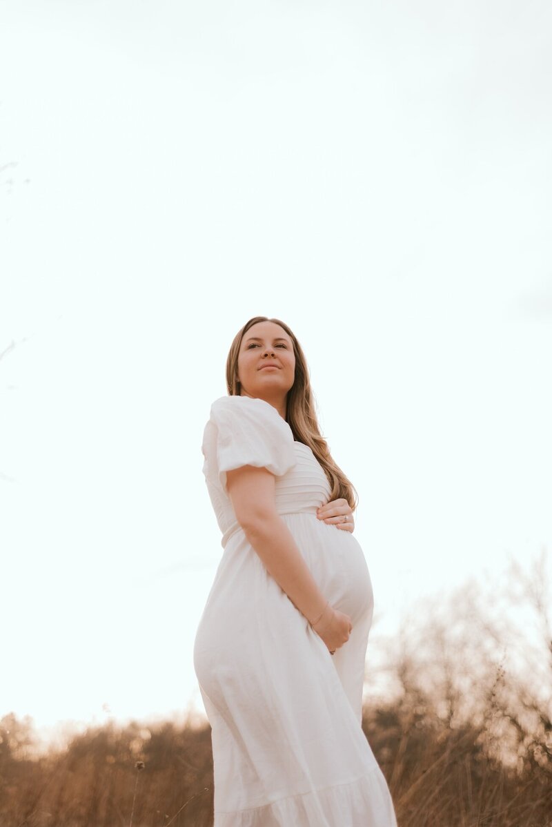 woman holds her pregnant belly during maternity shoot in peoria illinois