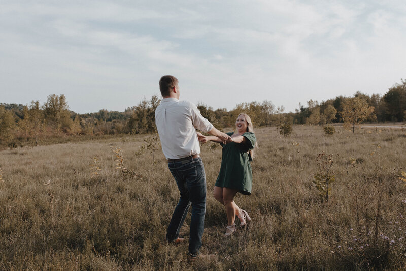 Couple spinning and laughing outside in a field