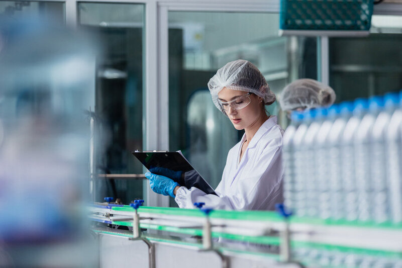 Trained engineer wearing blue checking a manufacturing machine