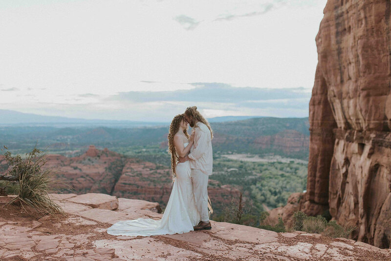 Wedding couple stand forehead to forehead in front of sedona landscape