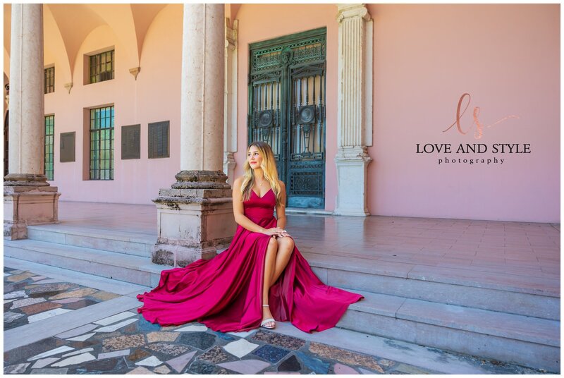 High school senior girl in magenta flowing dress seated in the courtyard at The Ringling museum in Sarasota, Fl.