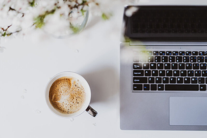Laptop and coffee mug over head view with plant 
