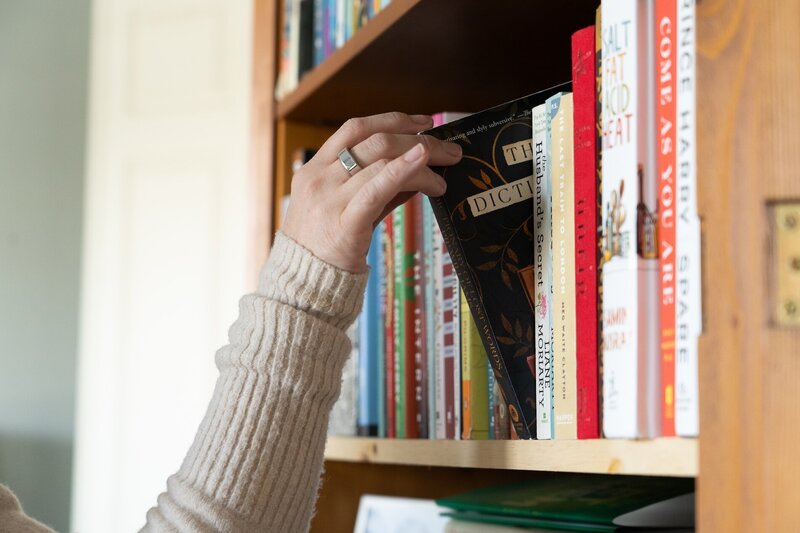 woman's hand pulling a book from a bookshelf