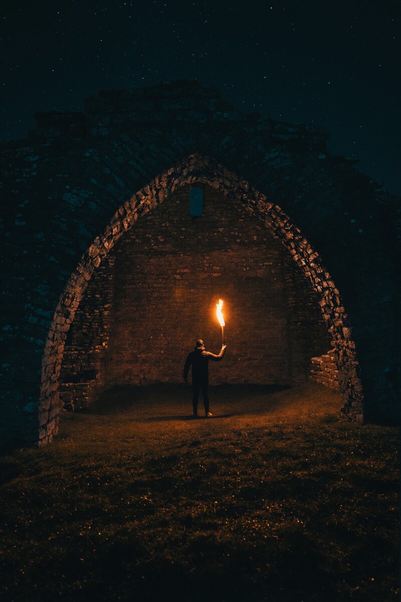 Dark cave or cavern with a person standing inside holding a flame torch