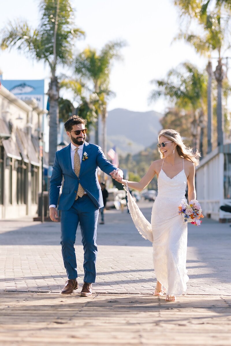 A bride and groom walk down the main road on Catalina Island on their wedding day.
