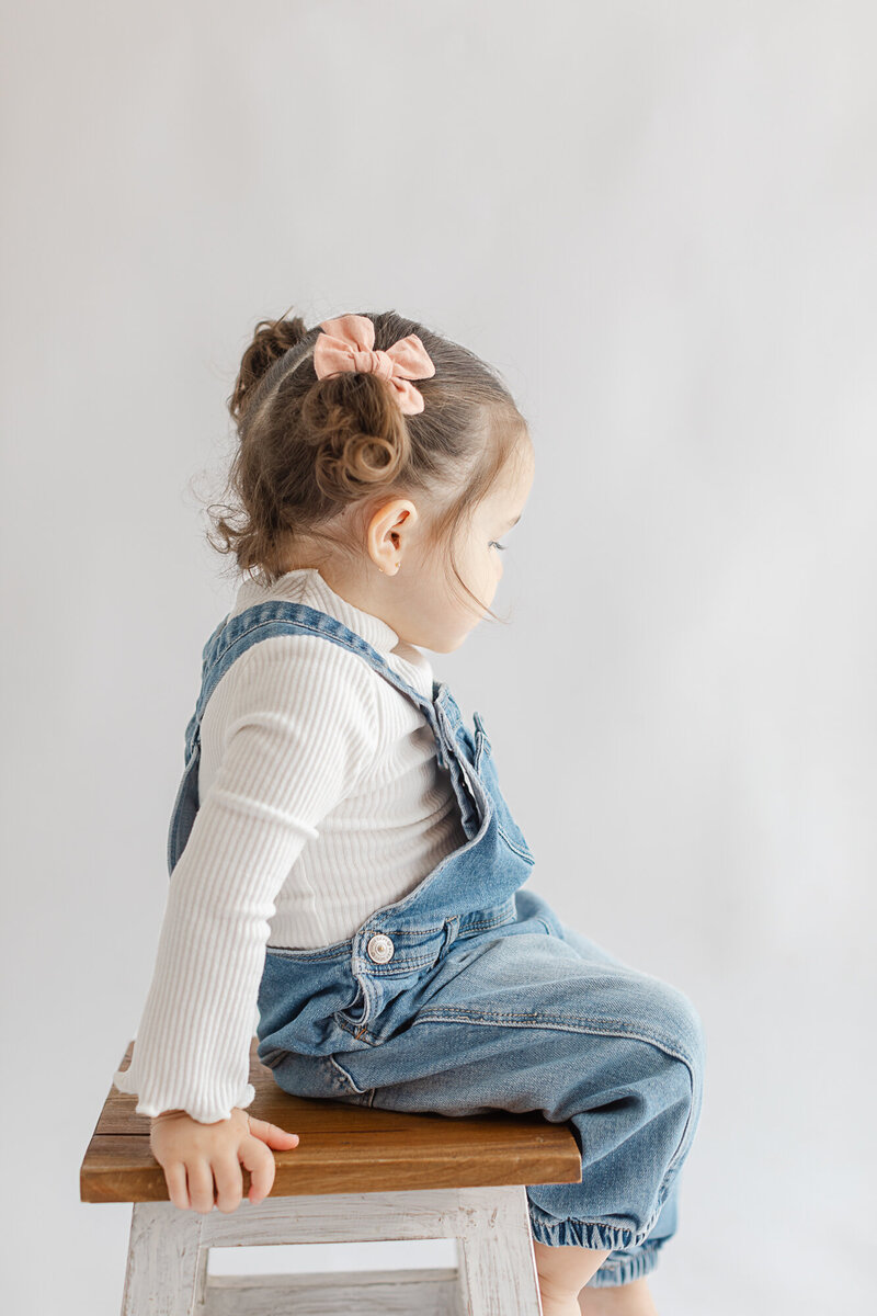 Toddler girl in Leesburg Studio sitting on a stool looking away from the camera