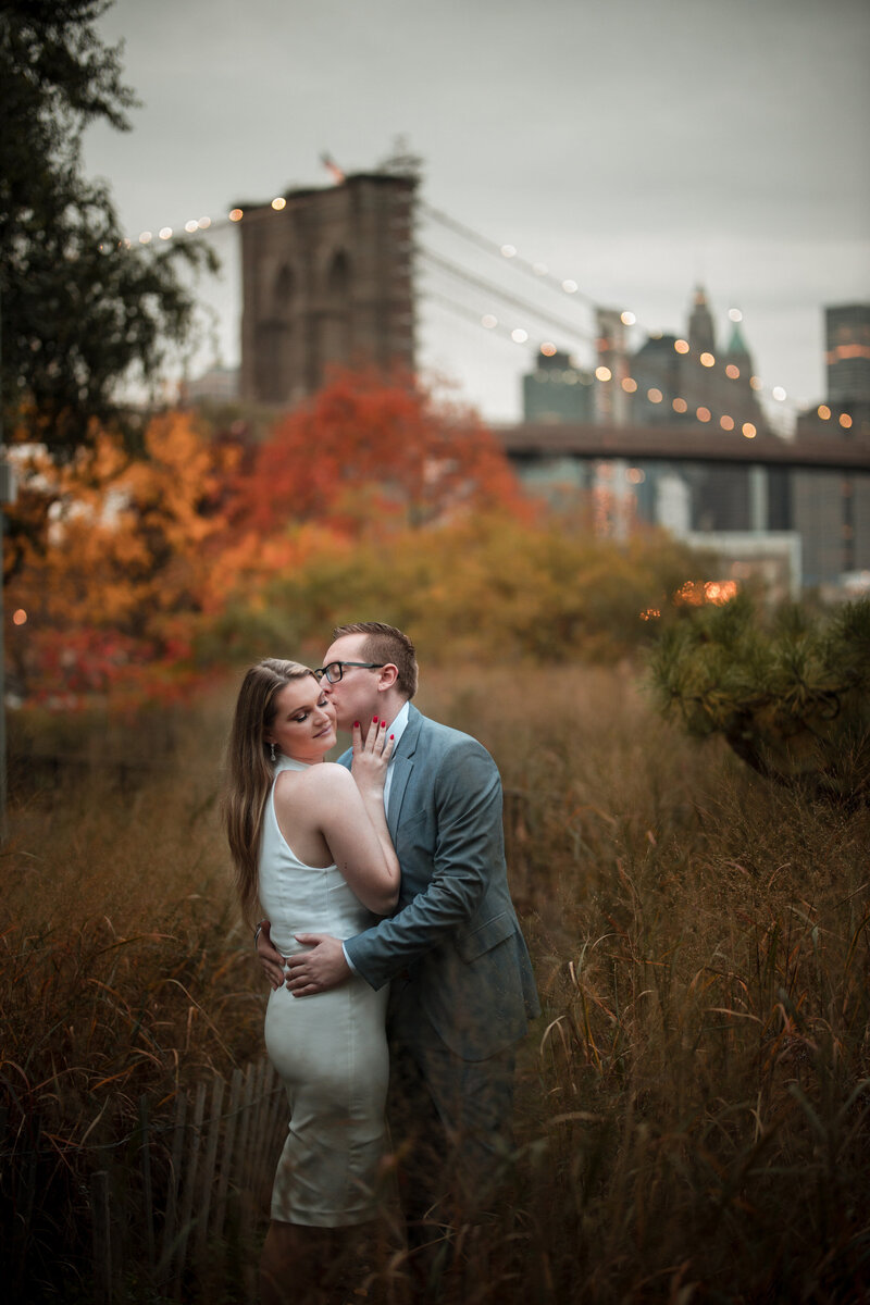 A couple walking along a sidewalk together with skyscrapers behind them.