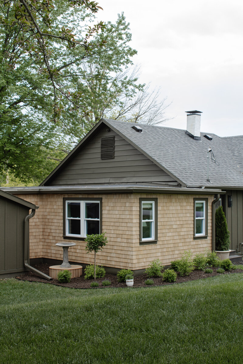 The exterior project by Nadine Stay. Board and batten siding install. Muddled Basil by Sherwin Williams exterior paint color. Flagstone path, brick front porch floor, and a custom built railing. Cabin exterior.
