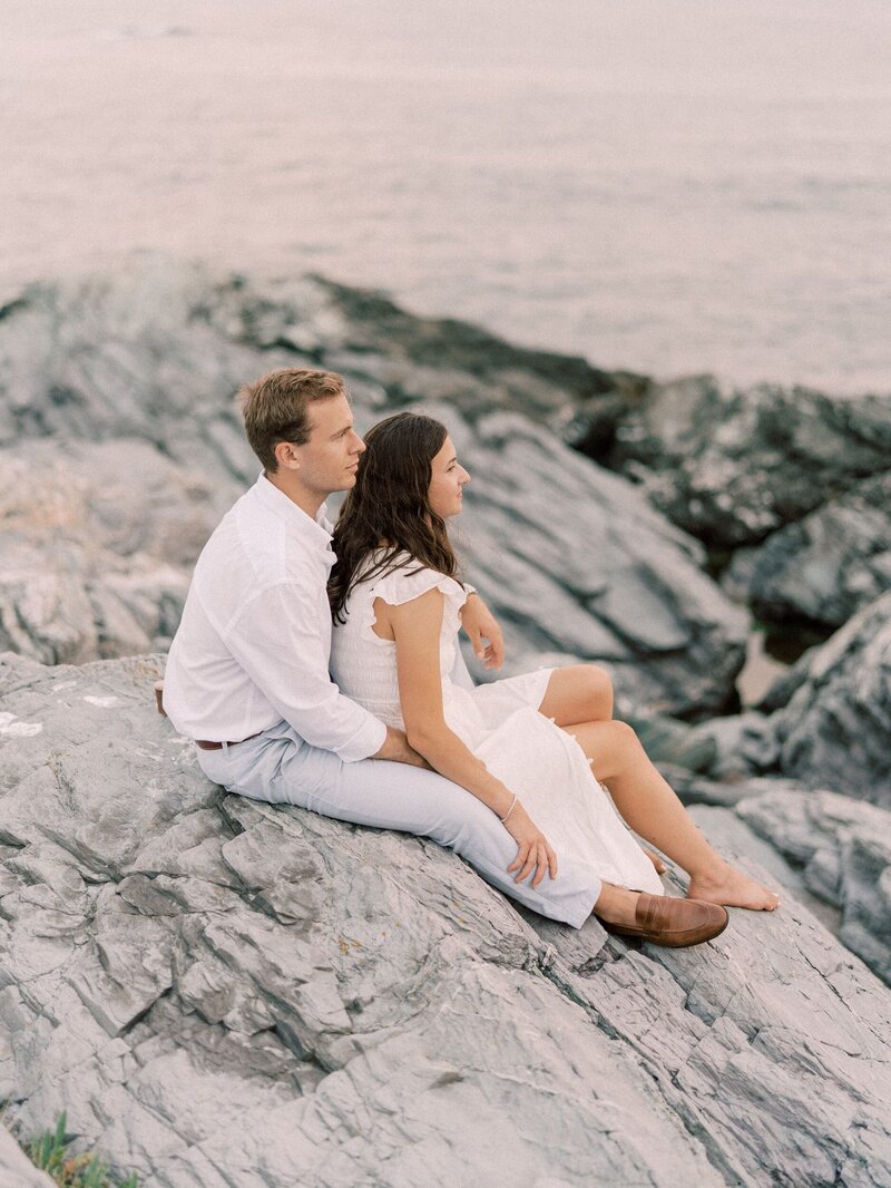 Newport engagement session couple sitting on rocks by the sea