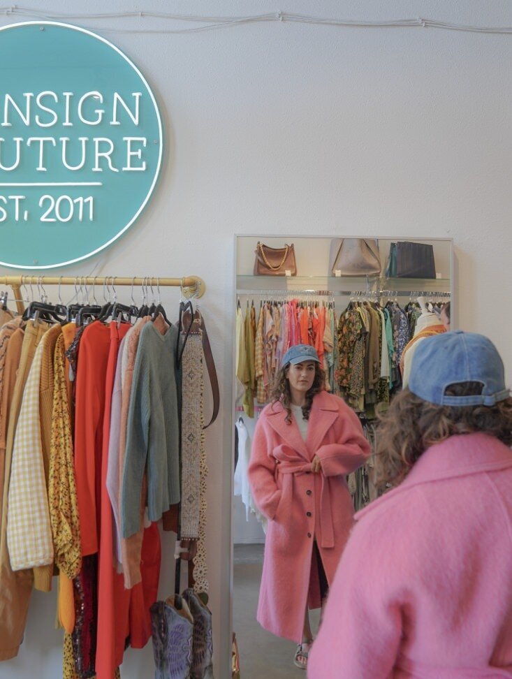 A person looking at themselves in a mirror as they try on a jacket in a store 