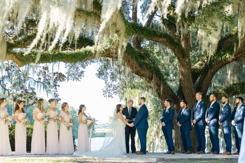 bride and groom holding hands during ceremony under the oak trees