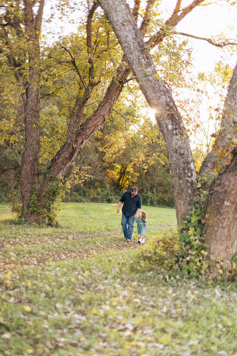 Portrait of a little girl holding her dad's hand and looking up at him in De Soto, Missouri. 