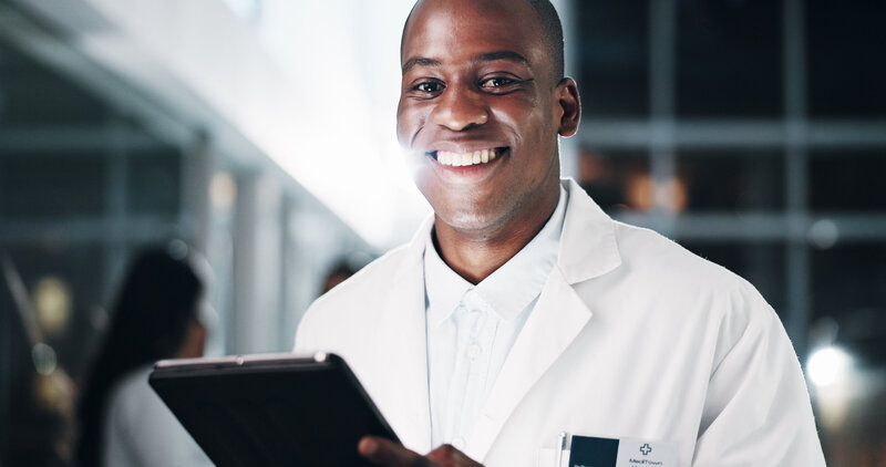 A healthcare professional in a doctor's coat, smiling at the camera, representing the compassionate and innovative approach of Occam Health Services.