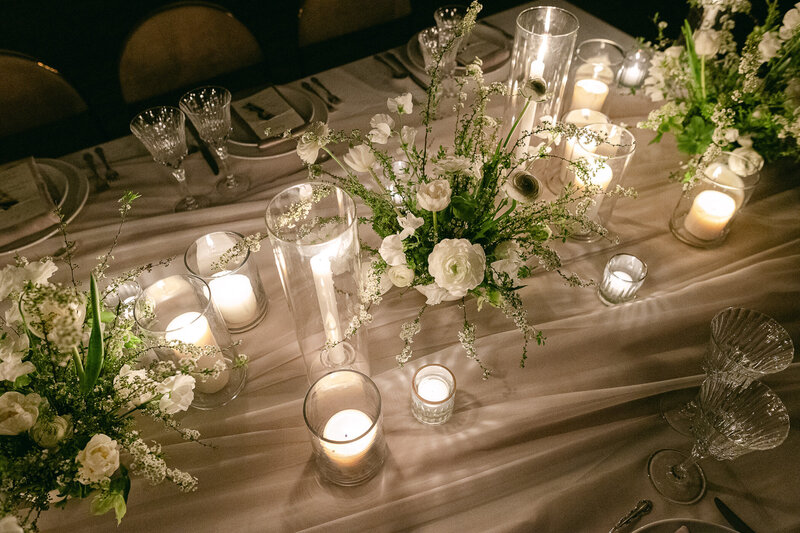 Une table bien décorée de chandelles, de couverts et de fleurs. Réception de mariage.