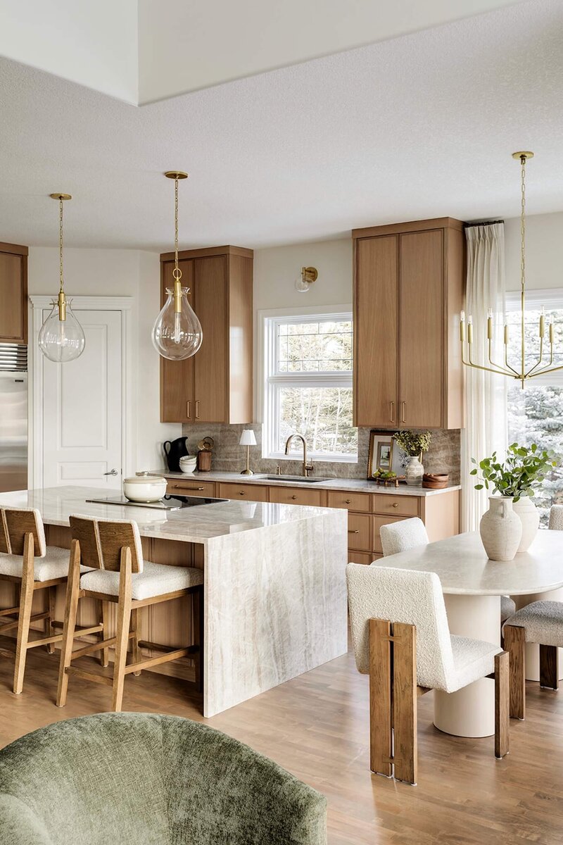 Kitchen renovation with quartzite, wooden counter stools, white oak cabinets and glass pendants. 