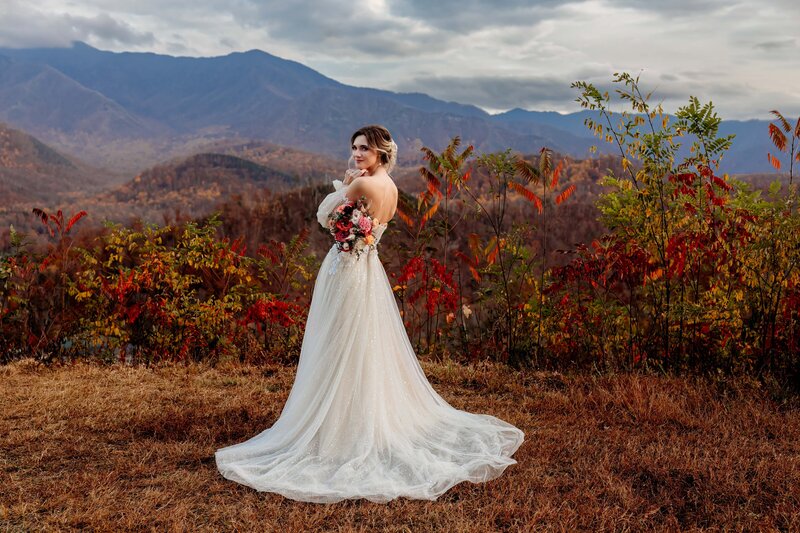 Elopement photographer, Bride standing in front of fall foliage with mountain in the background