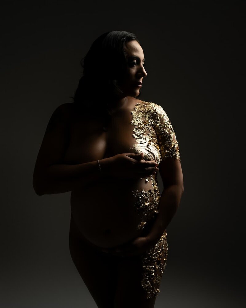Dramatic maternity photo featuring gold leaf foil and moody lighting – Hello Photography studio in Austin, Texas