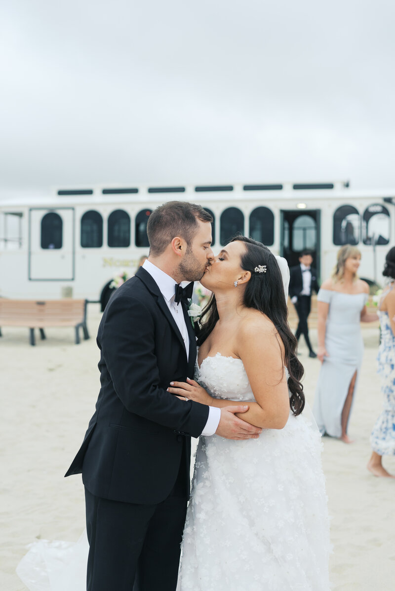 Bride and groom kissing in front of white trolley